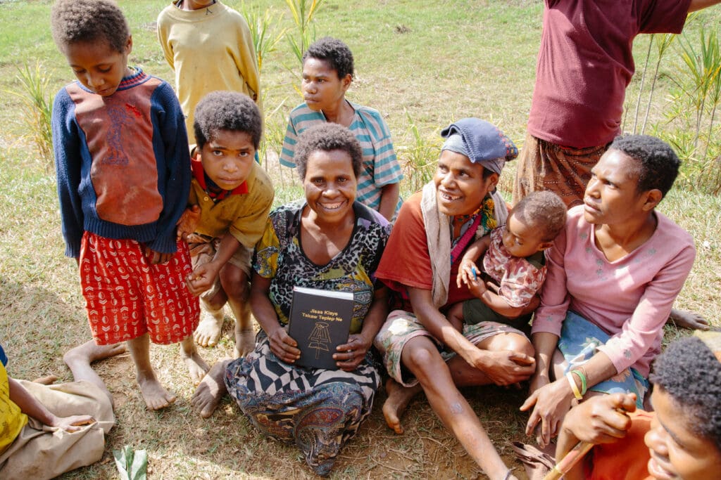 A Tay woman holding the Tay New Testament posing with others