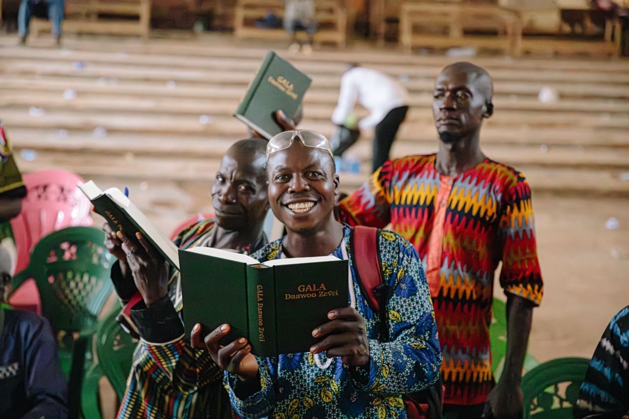 A group of people hold up their green bibles